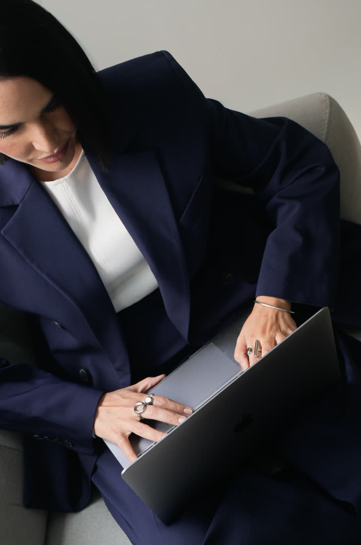 Mujer con saco azul marino trabajando en una laptop